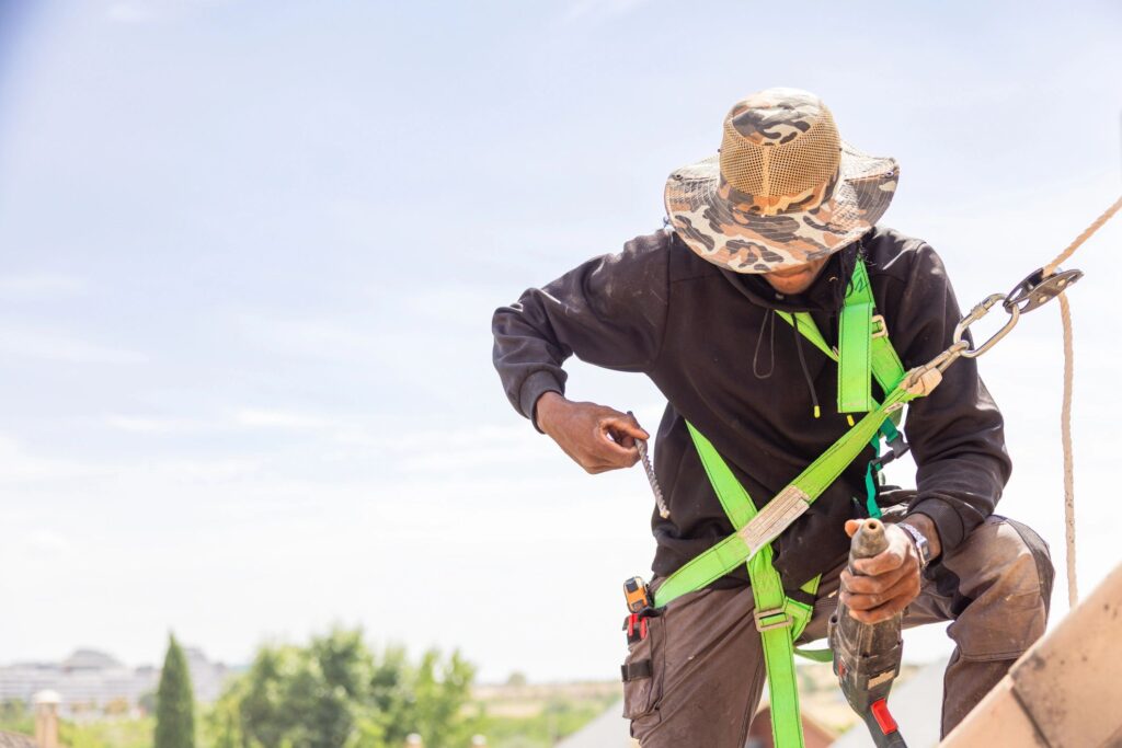 Roofer wearing safety equipment loading the drill with a drill bit